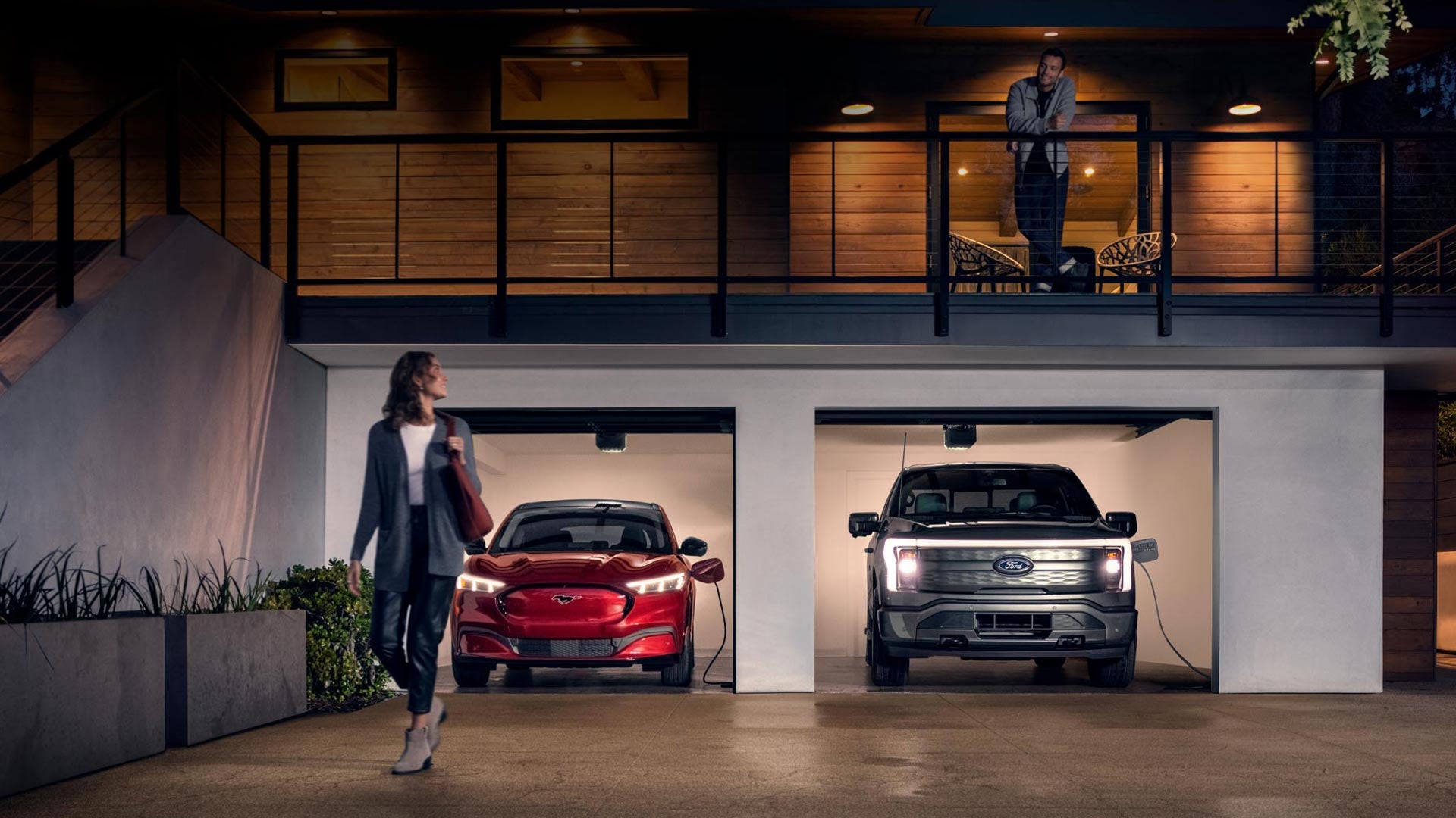Woman walking out from home garage with a 2024 Mustang® Mach-E and Ford Lightning® truck in plugged-in and charging | Long McArthur Ford in Salina KS